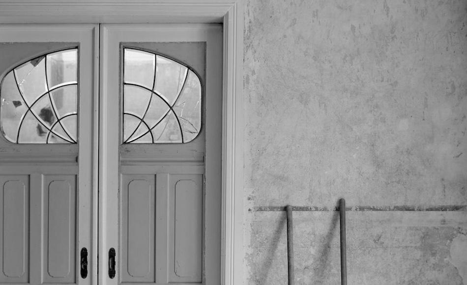 Tür mit Glasfenster und unrenovierter Wand in Schwarz-Weiß