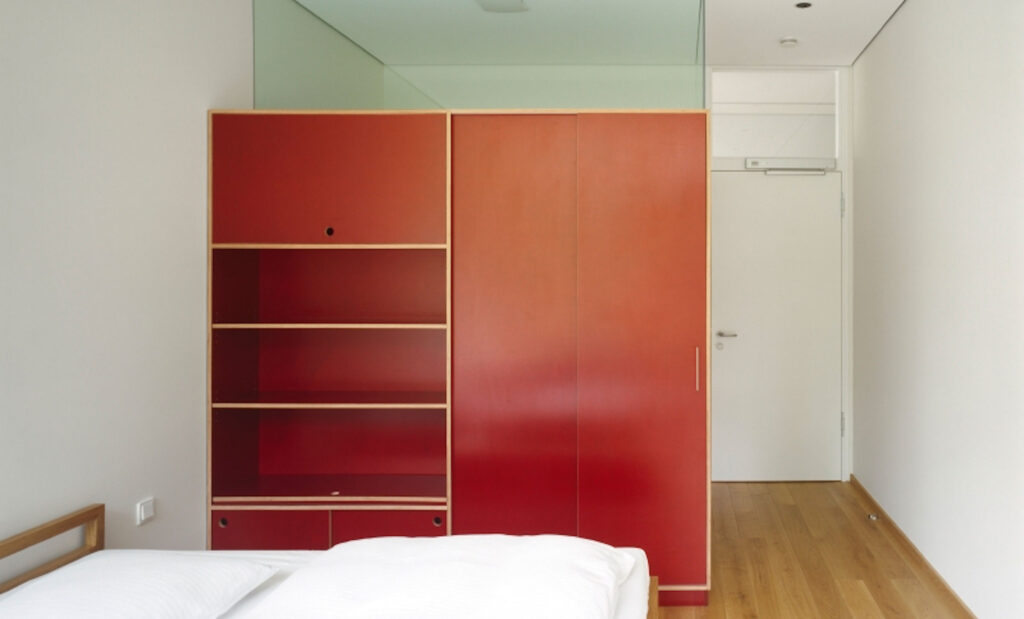 Ansicht eines Raumes mit rotem Schrank und Bett im Anschnitt
