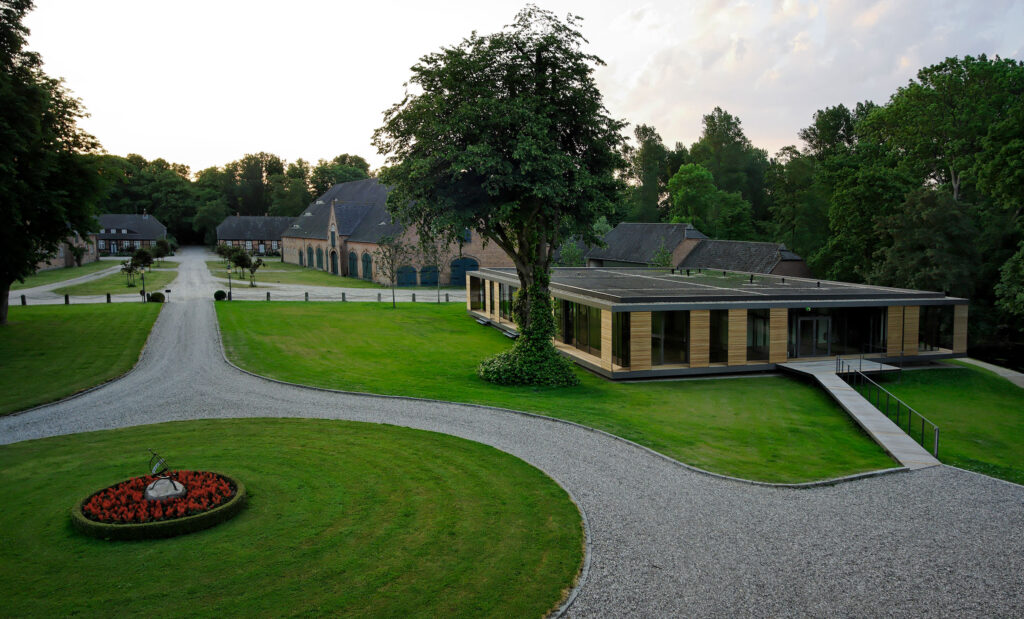 Blick von oben auf Seminargebäude Gut Siggen mit Rasen und Bäumen