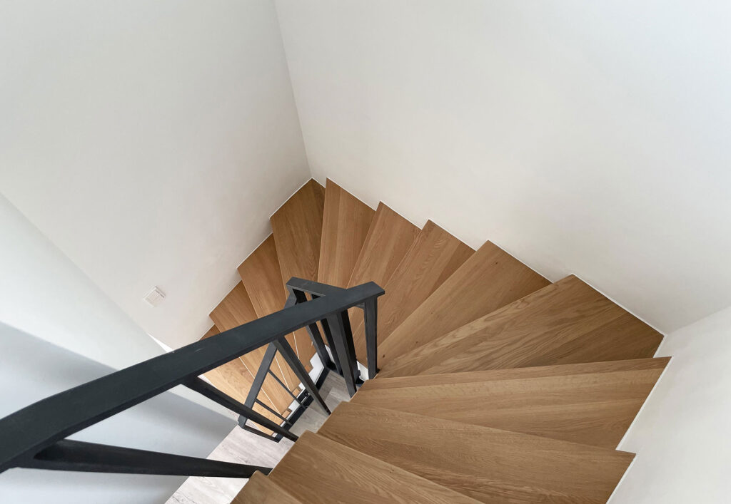 Blick von oben in ein treppenhaus mit Holzstufen und Metallgeländer