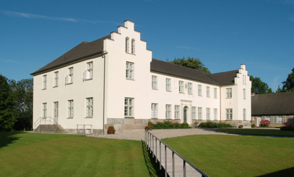 Außenansicht weißes Herrenhaus Gut Siggen, davor Rasen