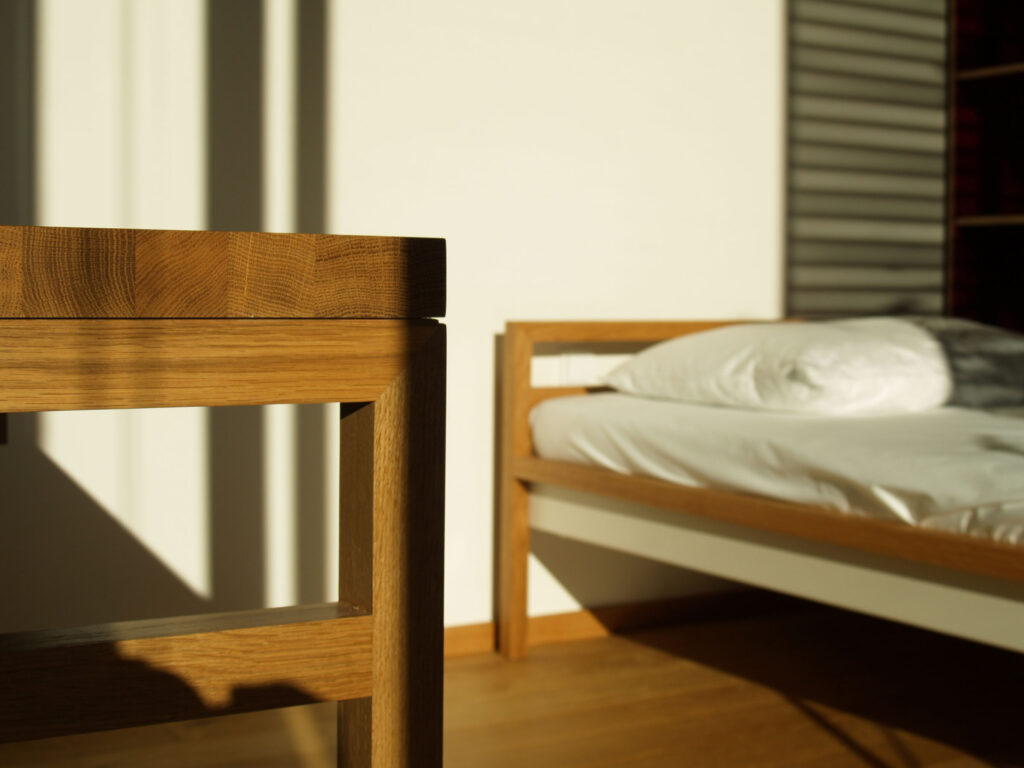 Detailansicht eines Schreibtisches - im Hintergrund ein Bett