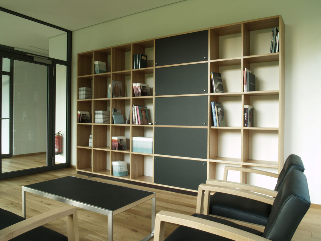 Wand mit Bücherregal und Tisch mit Sesseln im Vordergrund