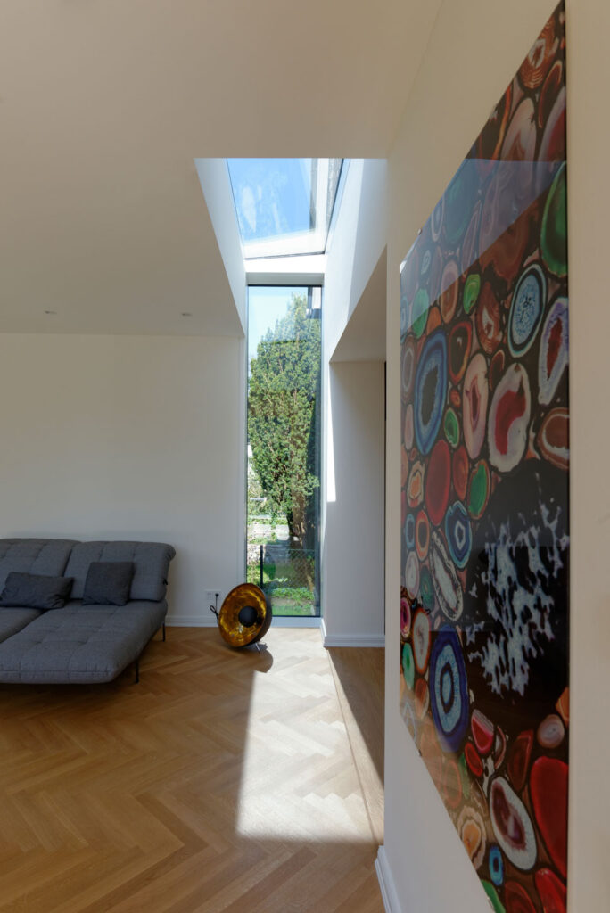 Blick auf ein Wohnzimmer mit Lichtfenster in Wand und Decke und Gemälde an der Wand