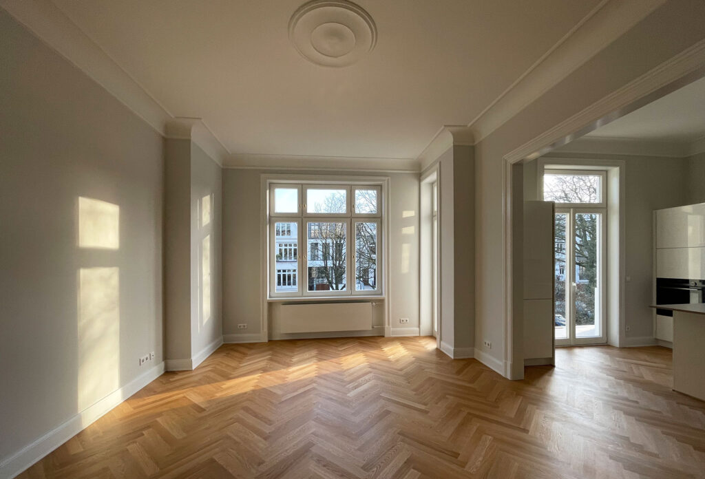 Blick in einen leeren Raum mit restauriertem Parkett - an der Decke Stuck