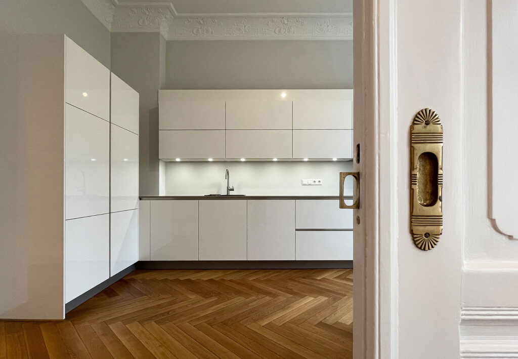 Blick in einen leeren Raum mit restauriertem Parkett - im Vordergrund eine halb geöffnete Schiebetür