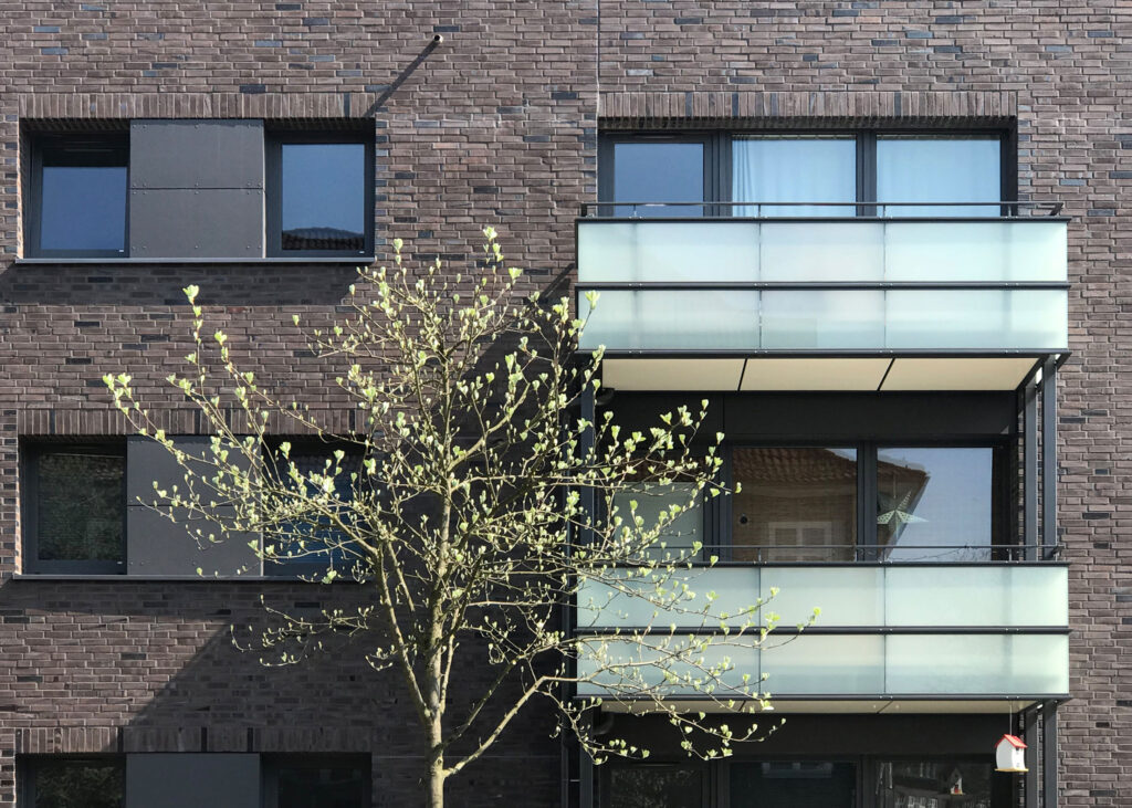 Blick auf Glasbalkone mit Baum im Vordergrund