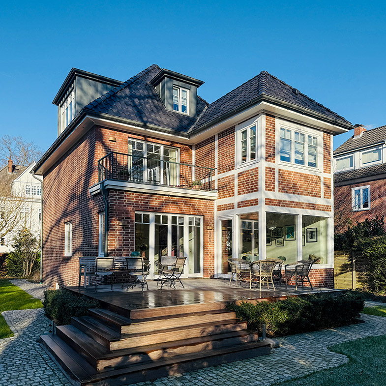 Blick auf ein saniertes Stadthaus aus den dreißiger Jahren mit Gartenterrasse.
